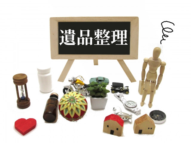 遺品整理と記載された看板と生活用品の模型に囲まれた人形